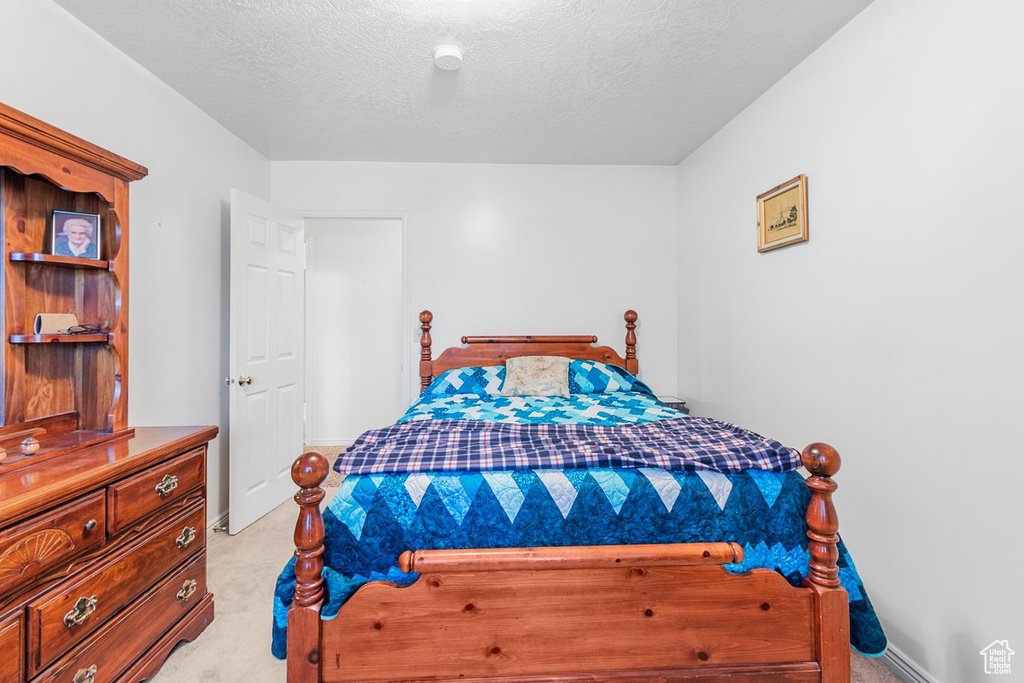 Bedroom featuring light carpet and a textured ceiling