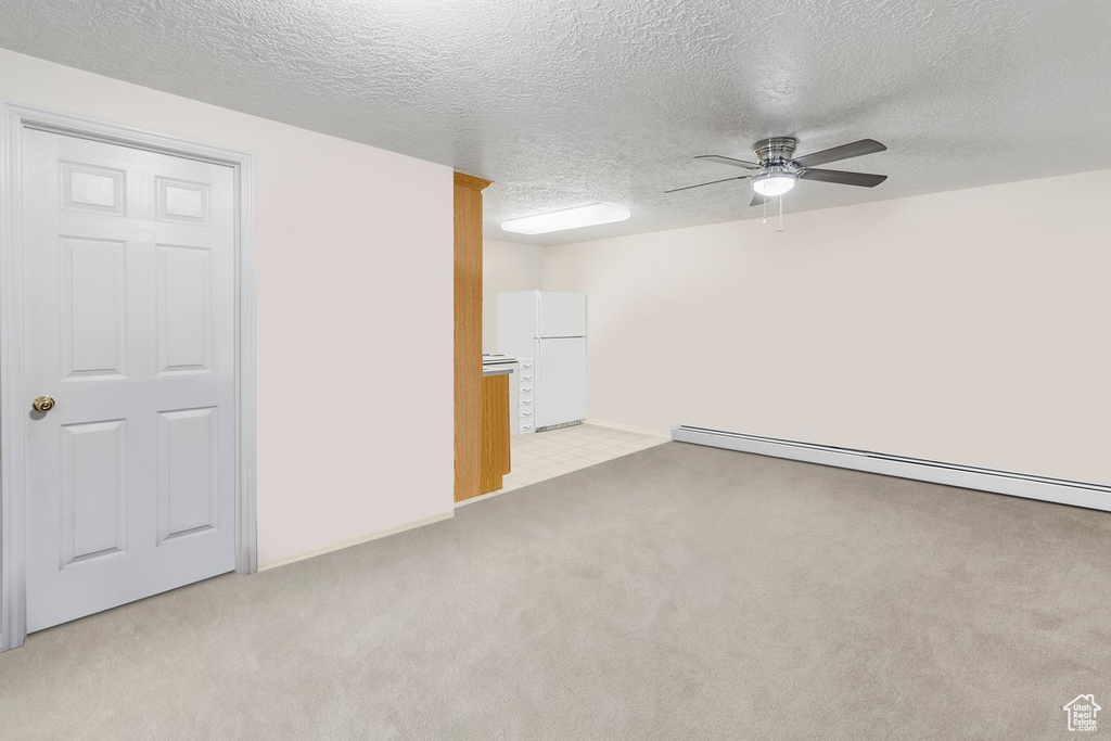 Carpeted empty room with a baseboard heating unit, a textured ceiling, and ceiling fan