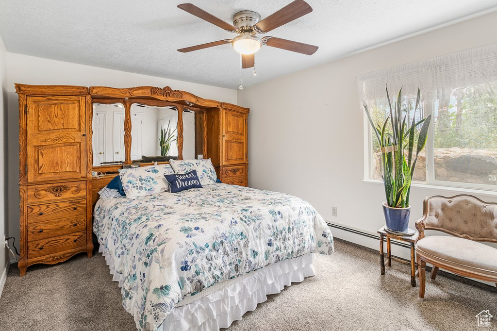 Bedroom with a baseboard radiator, a textured ceiling, ceiling fan, and light colored carpet