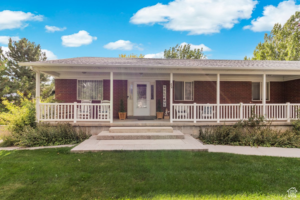 Ranch-style home featuring covered porch and a front lawn