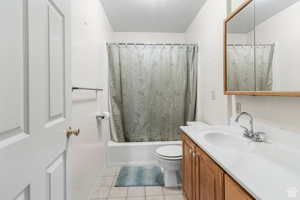 Full bathroom with shower / tub combo with curtain, vanity, toilet, a textured ceiling, and tile patterned flooring