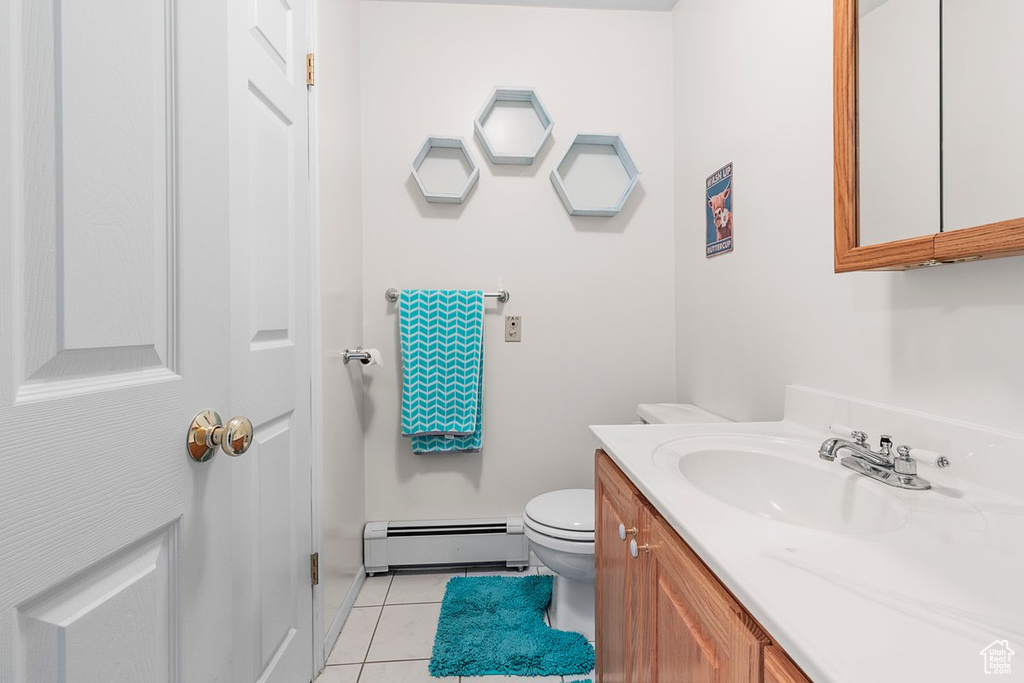 Bathroom with vanity, a baseboard radiator, toilet, and tile patterned flooring