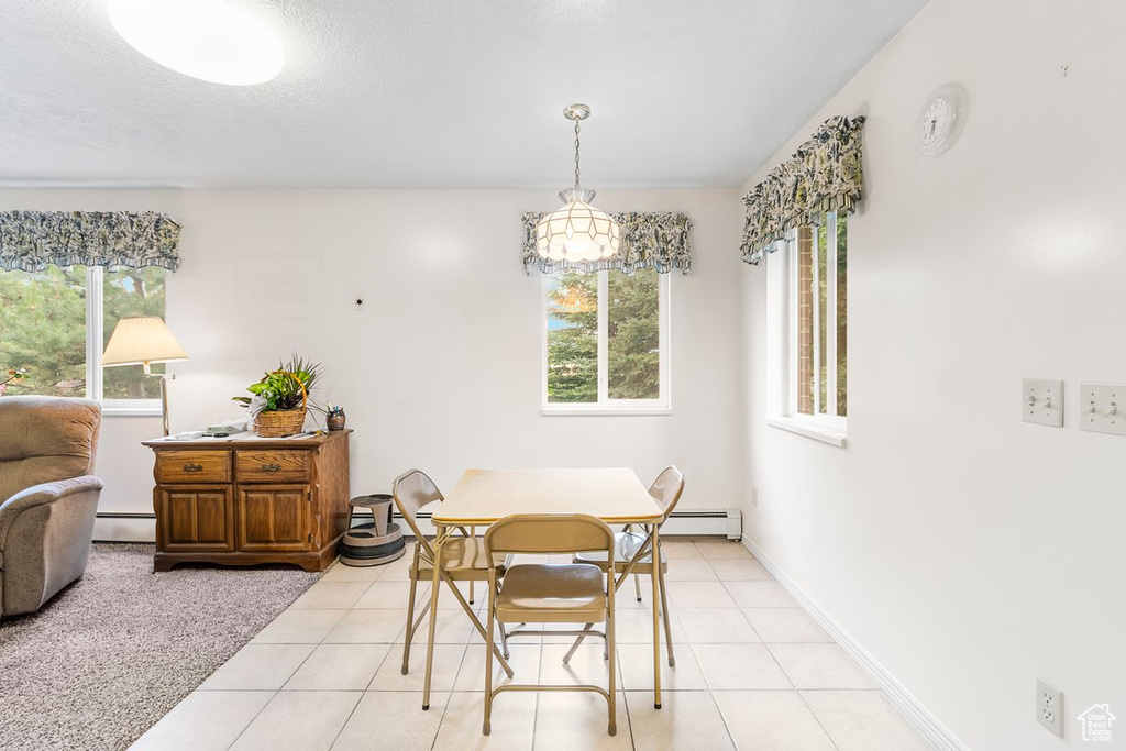 Dining space with a baseboard radiator and light tile patterned floors