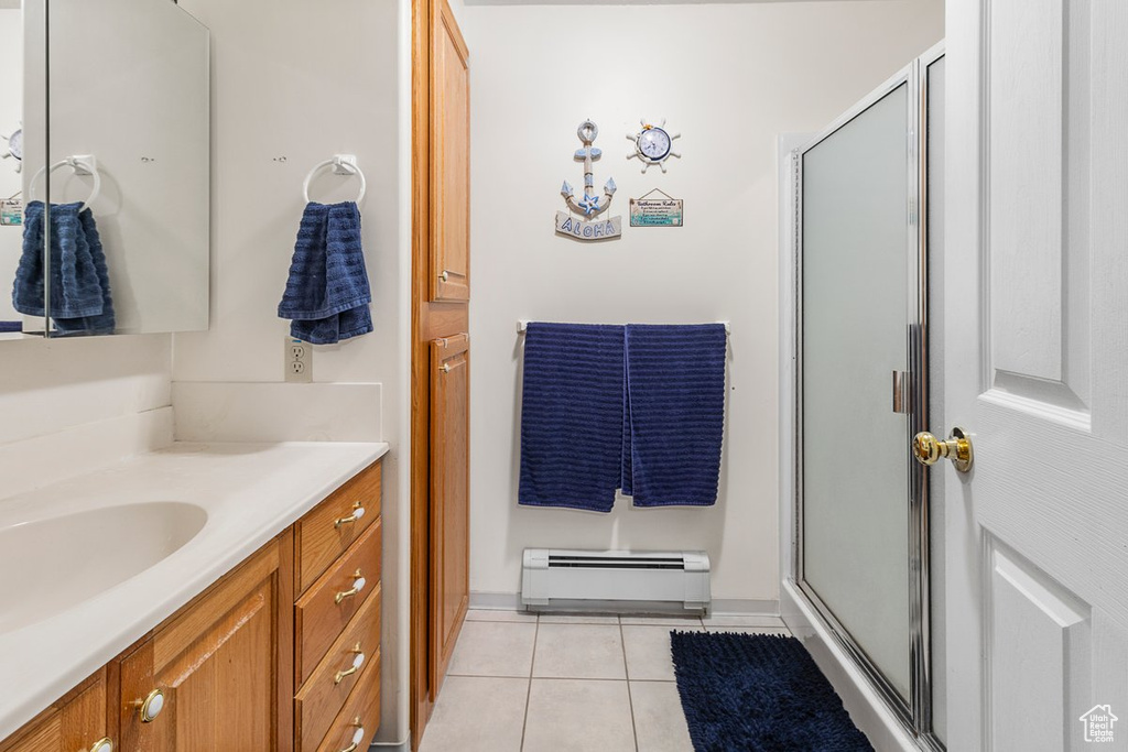 Bathroom with tile patterned flooring, baseboard heating, vanity, and a shower with shower door