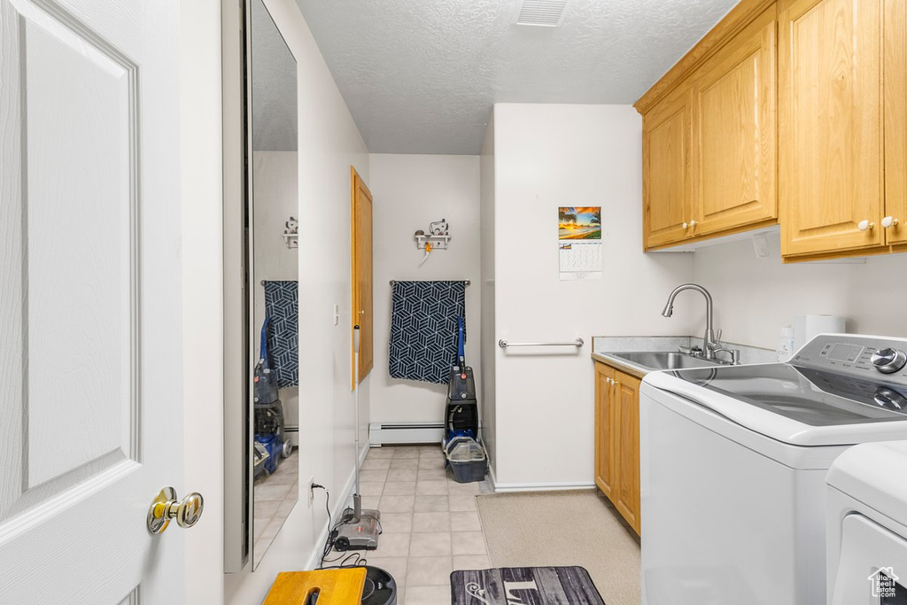 Laundry area featuring light tile patterned flooring, independent washer and dryer, a baseboard radiator, cabinets, and sink