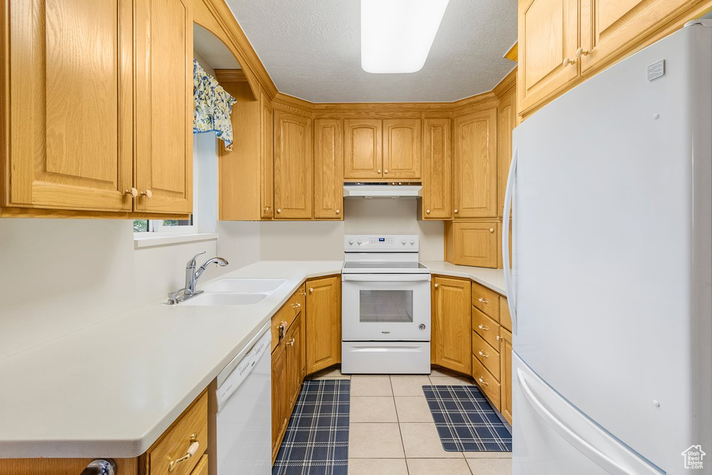 Kitchen featuring sink, light tile patterned flooring, and white appliances