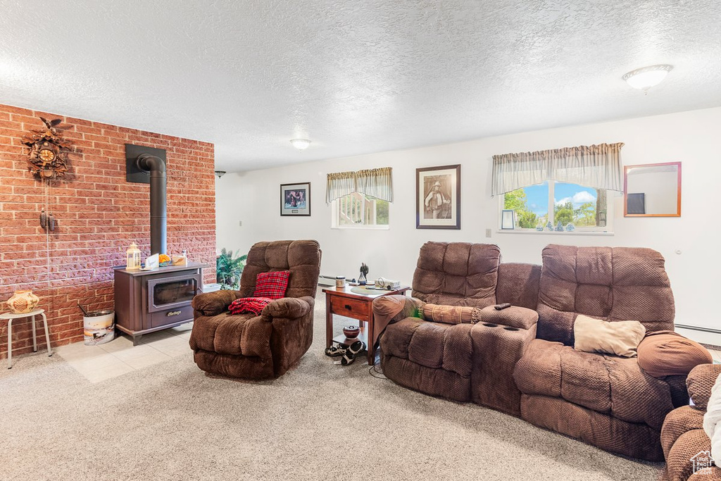 Living room featuring brick wall, light carpet, a wood stove, and a textured ceiling