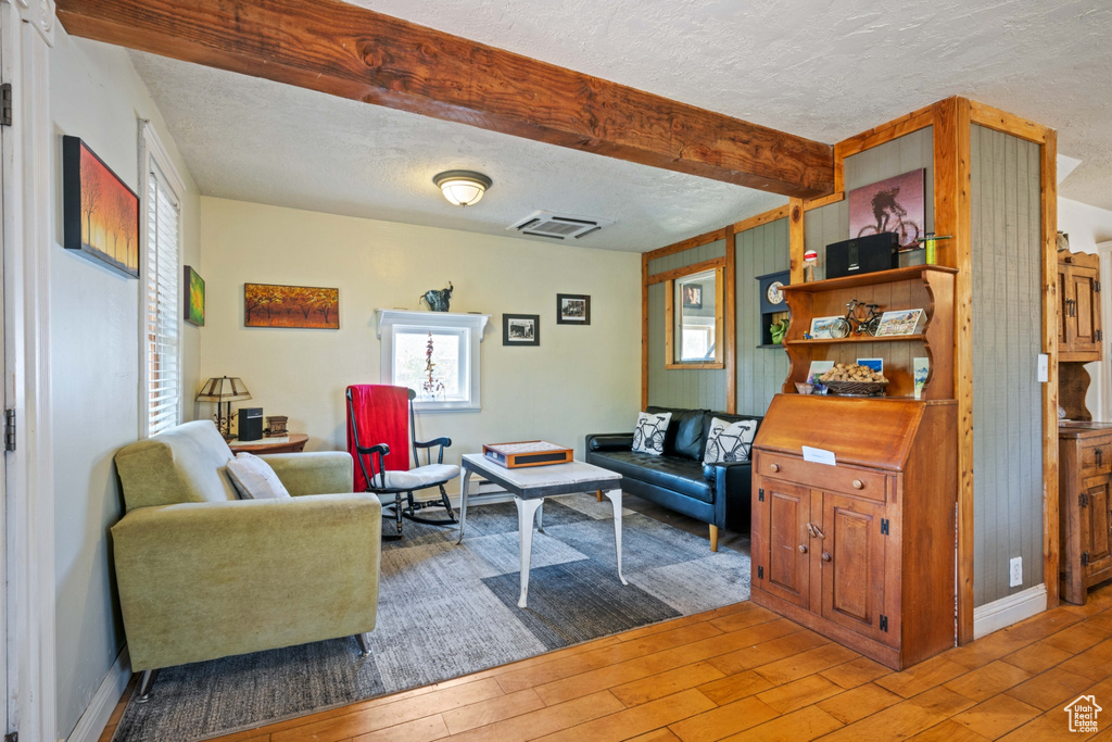 Living room featuring a textured ceiling, hardwood / wood-style flooring, and beam ceiling