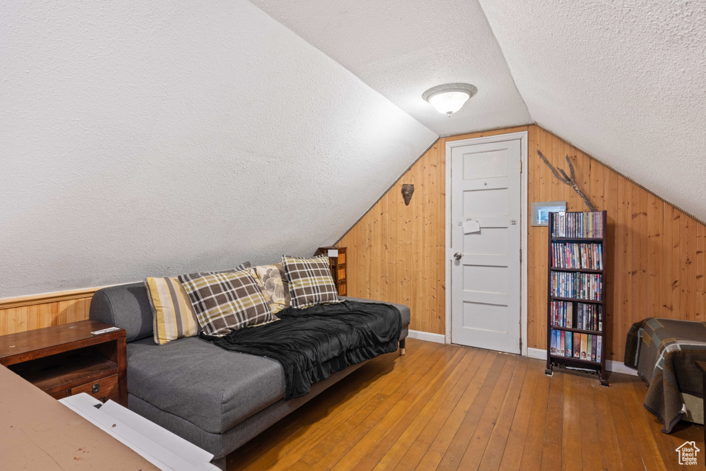 Interior space with wood walls, a textured ceiling, wood-type flooring, and vaulted ceiling