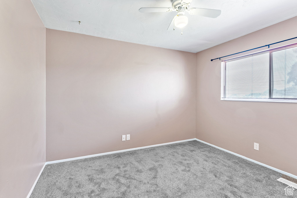 Carpeted empty room featuring ceiling fan