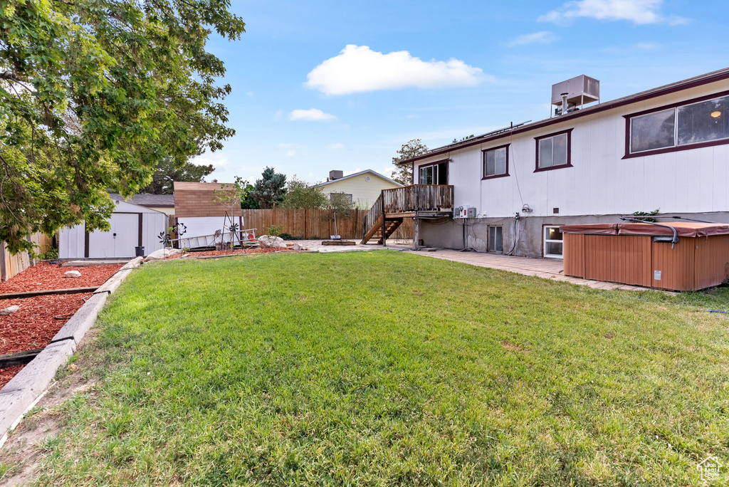 View of yard featuring a storage unit, a wooden deck, and a hot tub