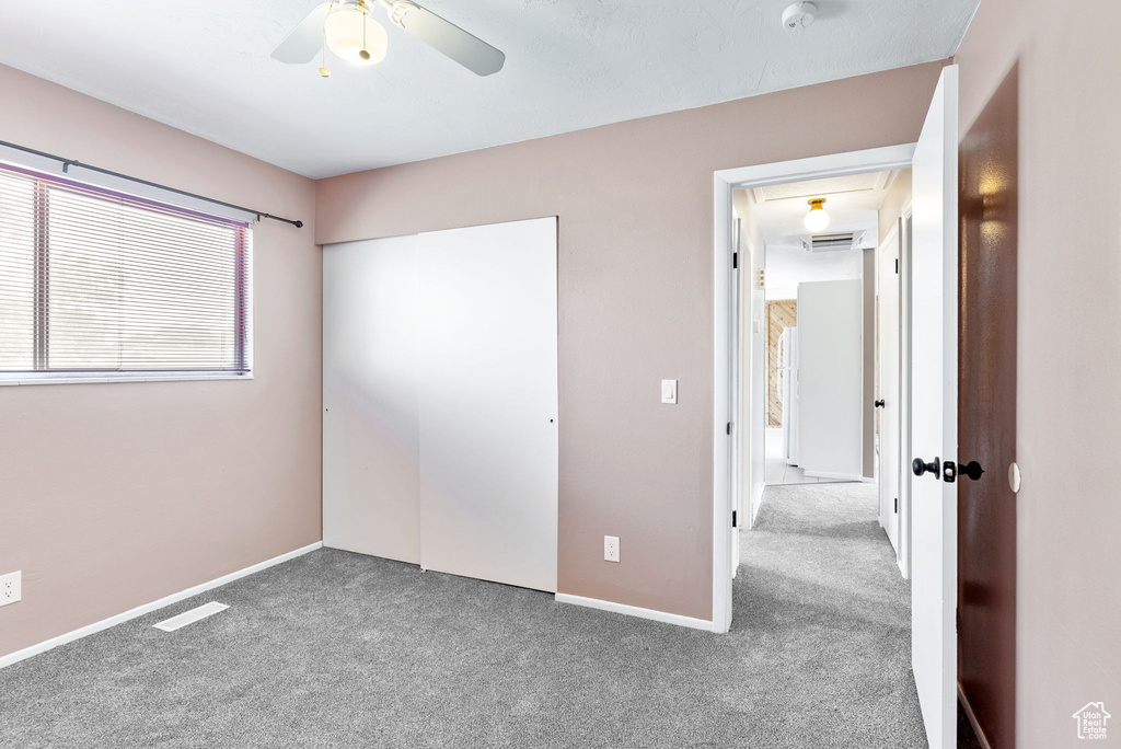 Unfurnished bedroom with carpet, a closet, and ceiling fan