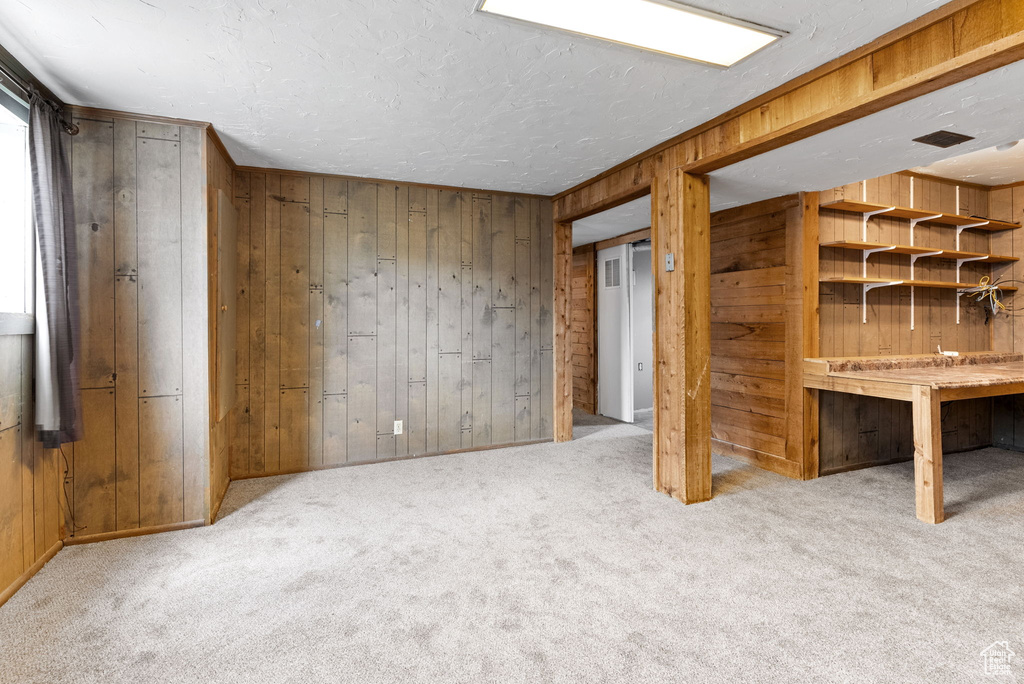 Basement featuring carpet, a textured ceiling, and wooden walls