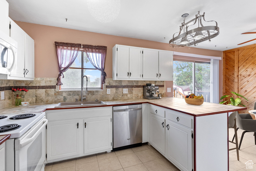 Kitchen with white cabinets, kitchen peninsula, and white appliances