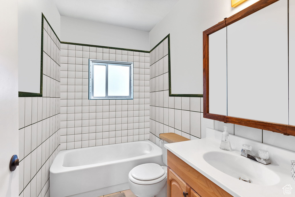 Full bathroom featuring tile walls, vanity, toilet, and tiled shower / bath combo