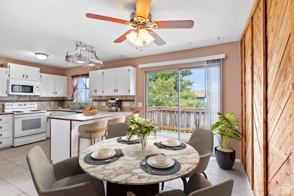 Kitchen with a healthy amount of sunlight, white appliances, white cabinetry, and decorative backsplash