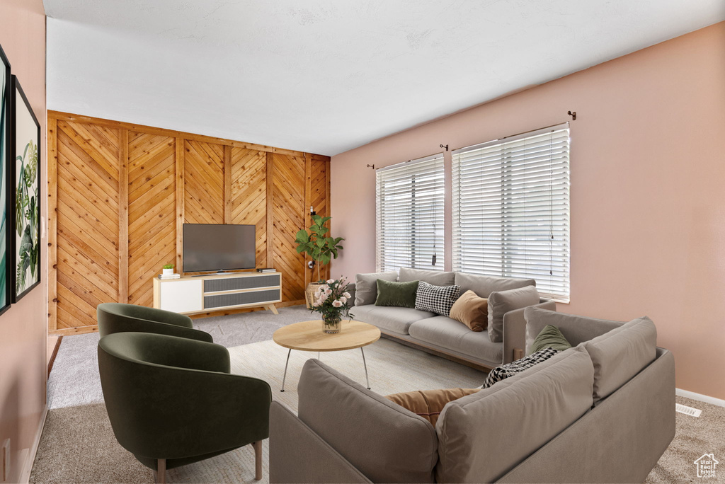 Living room featuring wooden walls and light colored carpet