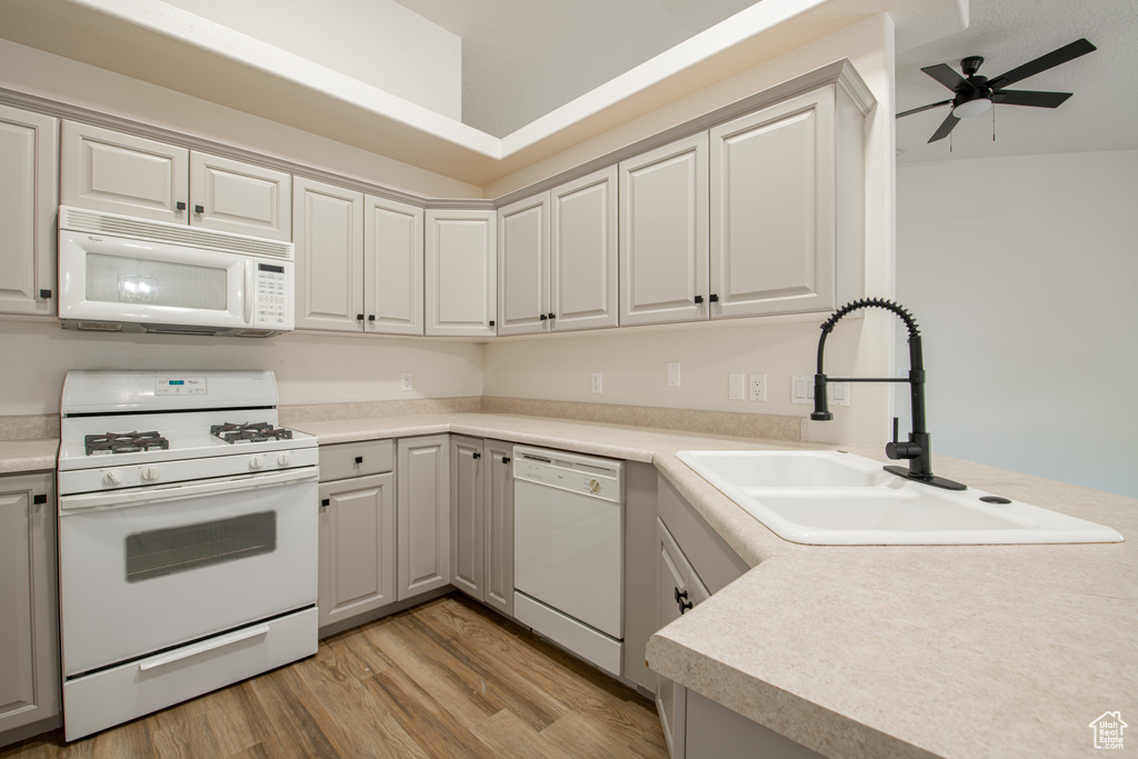 Kitchen featuring ceiling fan, white appliances, sink, light hardwood / wood-style flooring, and gray cabinetry