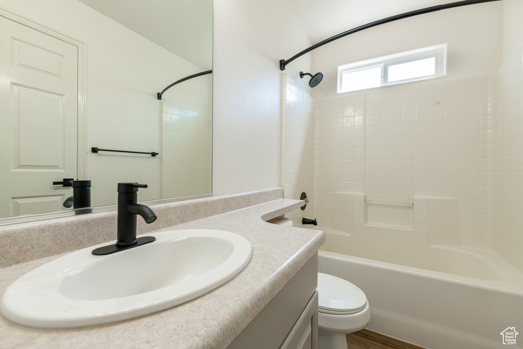 Full bathroom with bathing tub / shower combination, vanity, hardwood / wood-style floors, and toilet