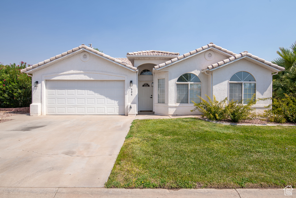 Mediterranean / spanish house featuring a garage and a front lawn