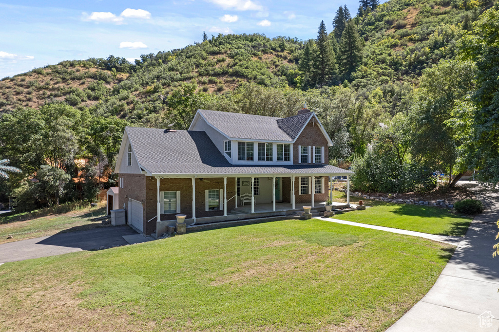 View of front of home with a garage, a front lawn, and covered porch