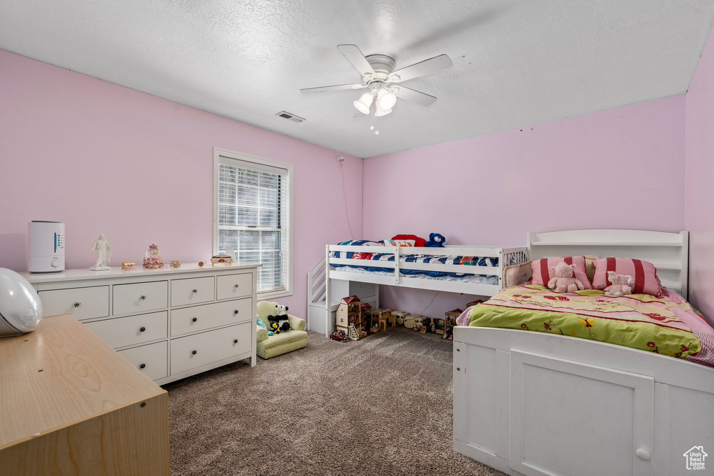 Bedroom featuring a textured ceiling, carpet floors, and ceiling fan