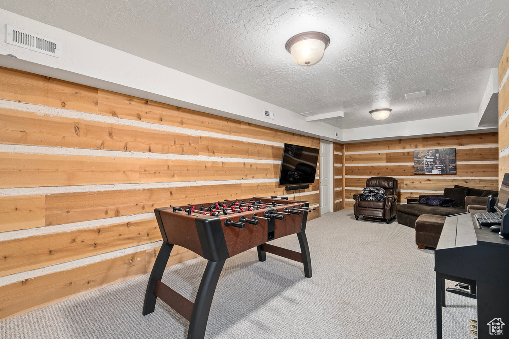 Game room featuring a textured ceiling, carpet floors, and wooden walls