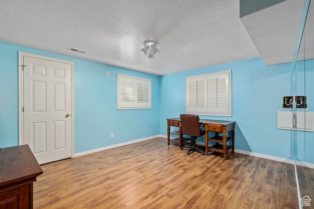 Home office with a textured ceiling and wood-type flooring