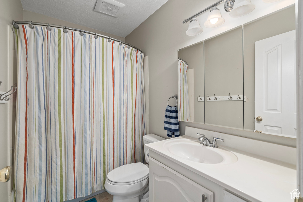 Bathroom featuring a textured ceiling, vanity, and toilet