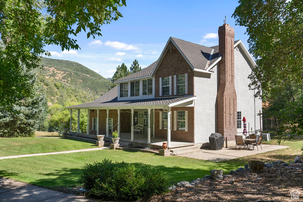 Back of property featuring a mountain view and a yard