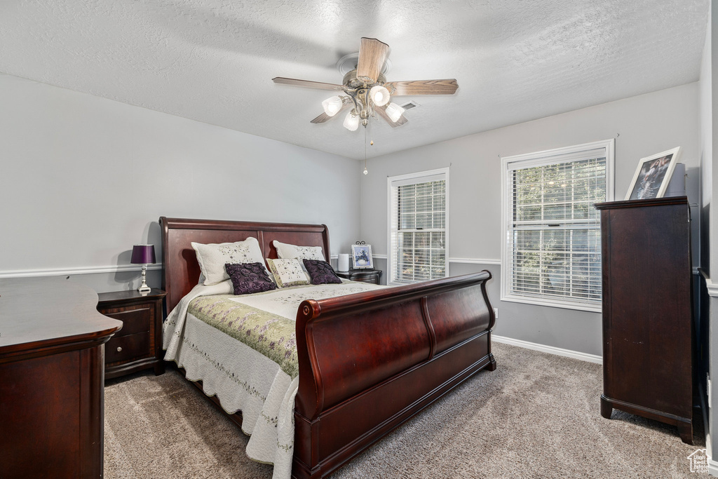 Bedroom with ceiling fan, a textured ceiling, and light colored carpet