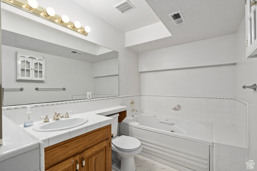 Bathroom featuring a bathing tub, toilet, tile patterned flooring, and vanity