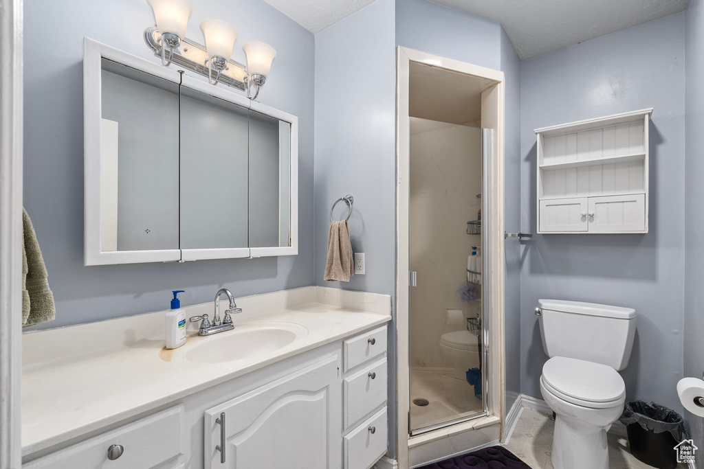 Bathroom with tile patterned flooring, a shower with door, toilet, and vanity