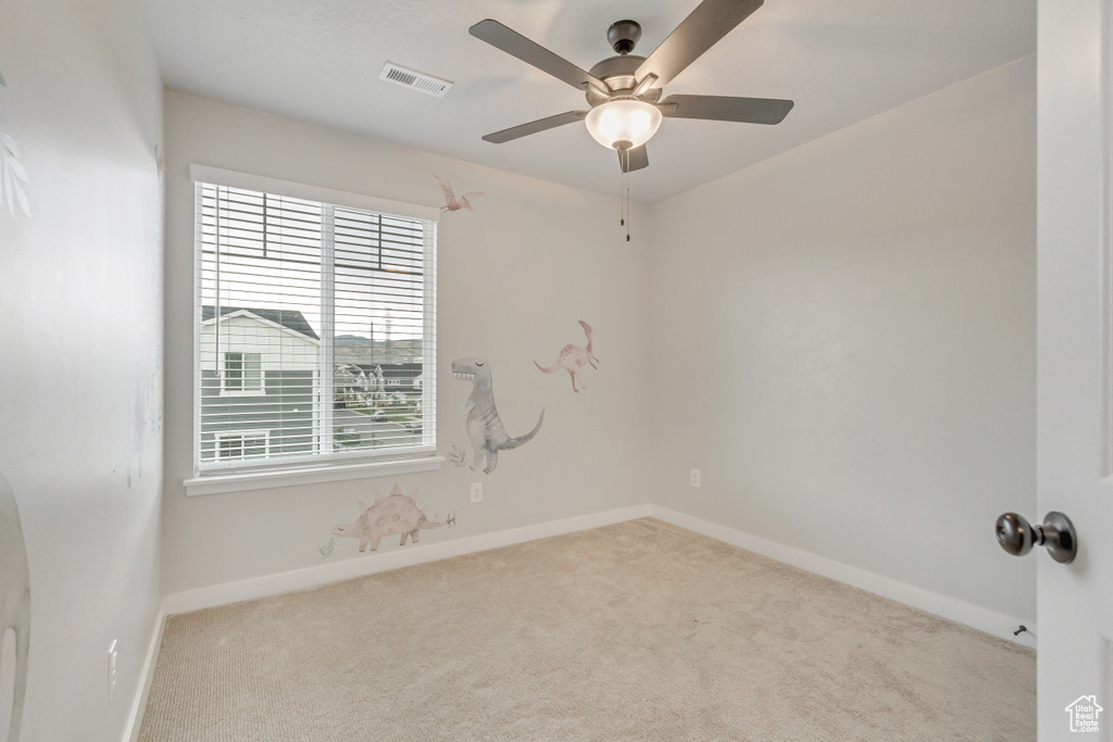 Carpeted spare room with a healthy amount of sunlight and ceiling fan