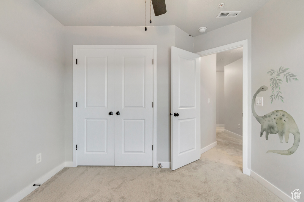 Unfurnished bedroom featuring carpet floors, ceiling fan, and a closet