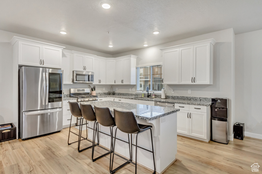 Kitchen featuring a kitchen island, appliances with stainless steel finishes, a breakfast bar area, and light hardwood / wood-style floors