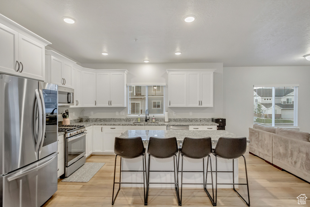 Kitchen with a kitchen bar, a kitchen island, stainless steel appliances, and light hardwood / wood-style floors