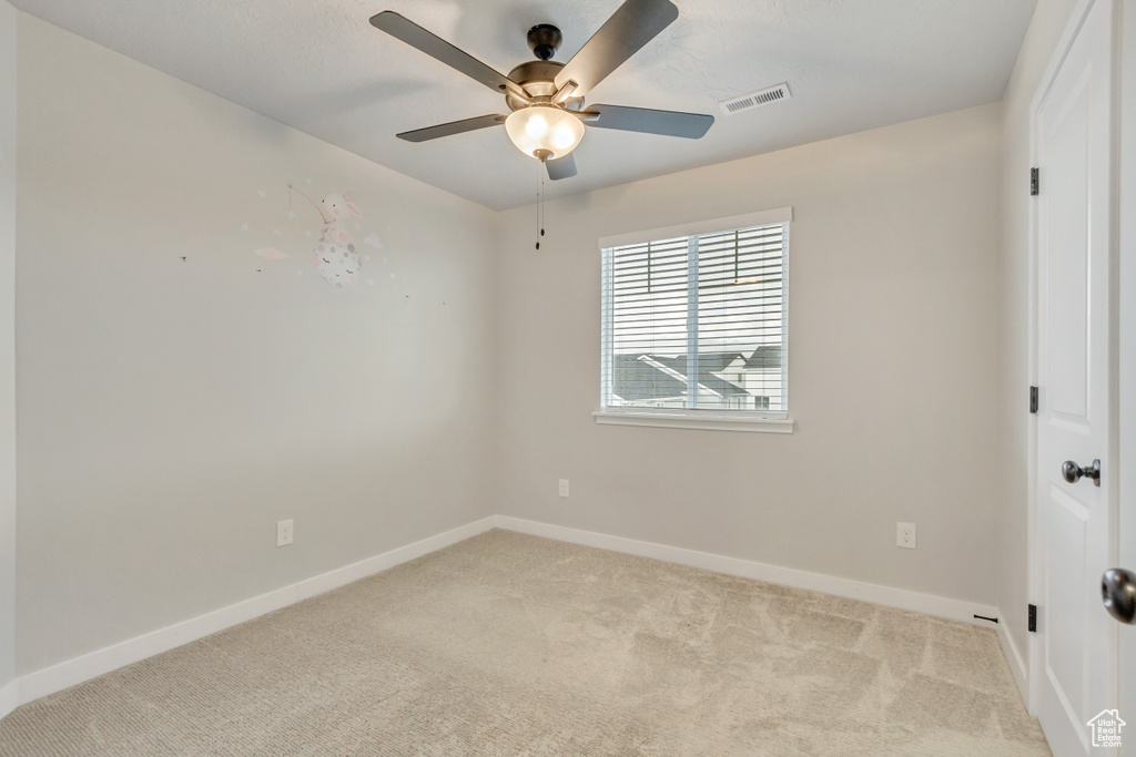 Carpeted empty room featuring ceiling fan