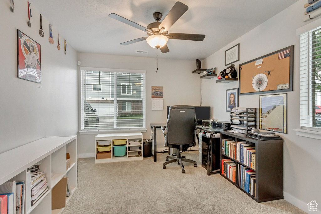 Carpeted home office featuring ceiling fan