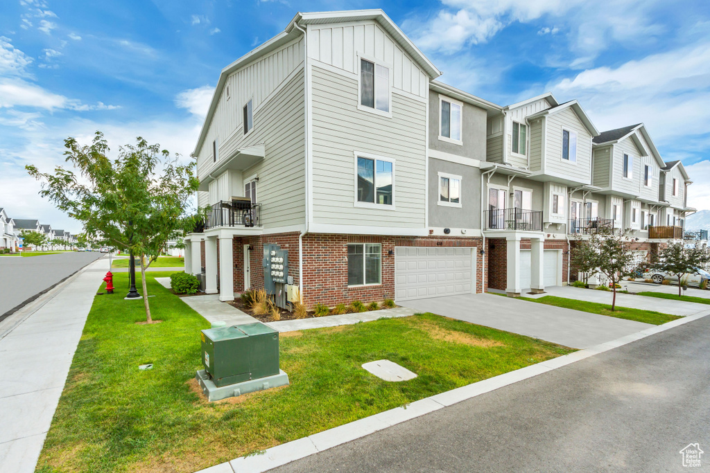 View of property with a balcony, a garage, and a front yard