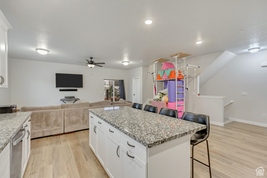 Kitchen featuring a kitchen bar, white cabinets, light wood-type flooring, and ceiling fan