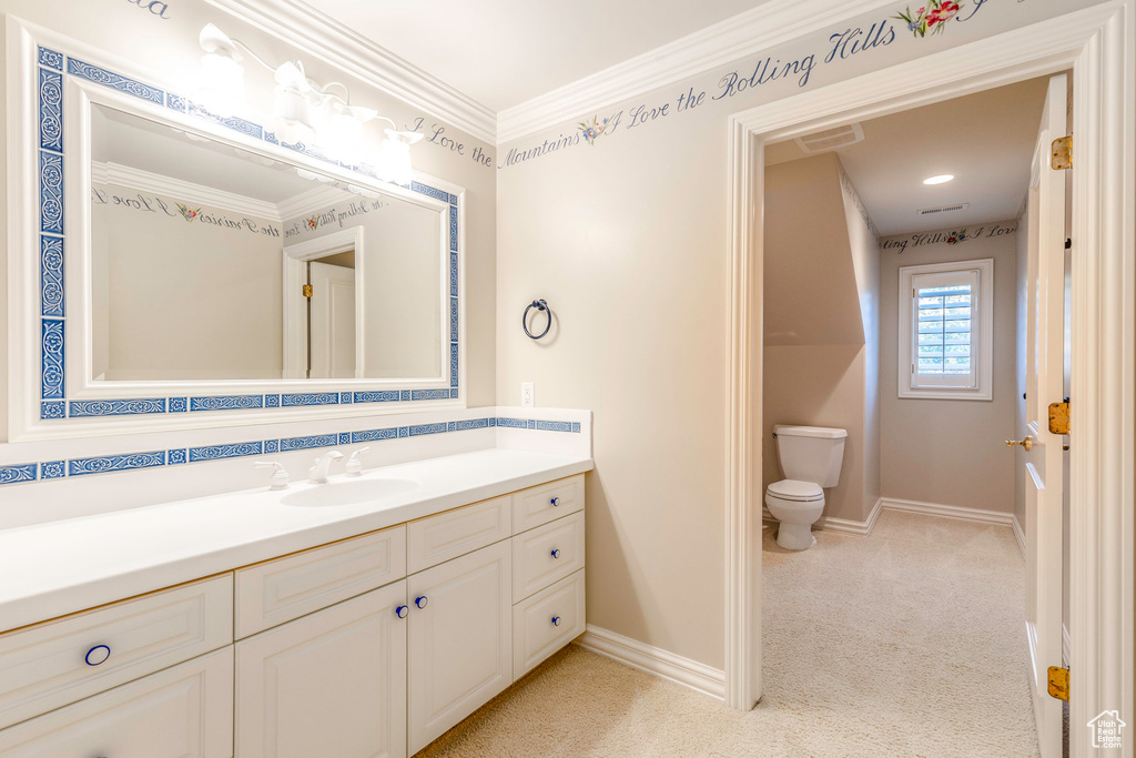 Bathroom with ornamental molding, vanity, and toilet