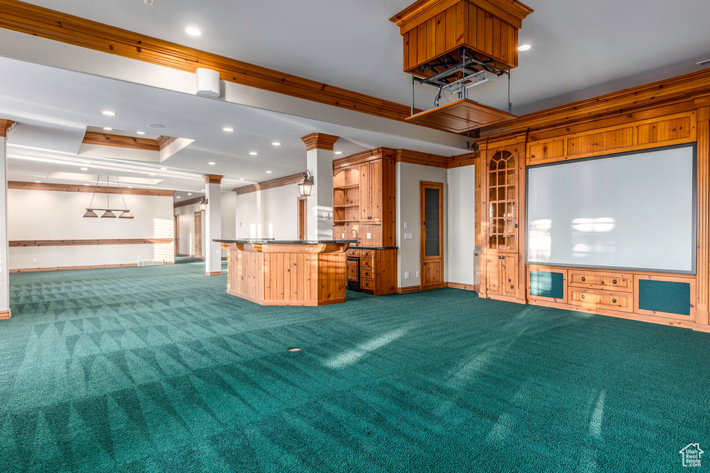 Interior space featuring decorative columns, a raised ceiling, crown molding, and carpet floors