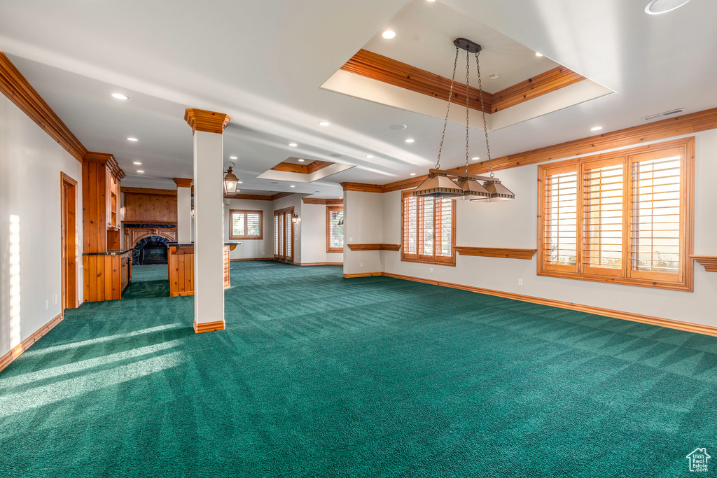 Unfurnished living room featuring dark carpet, ornamental molding, and a tray ceiling