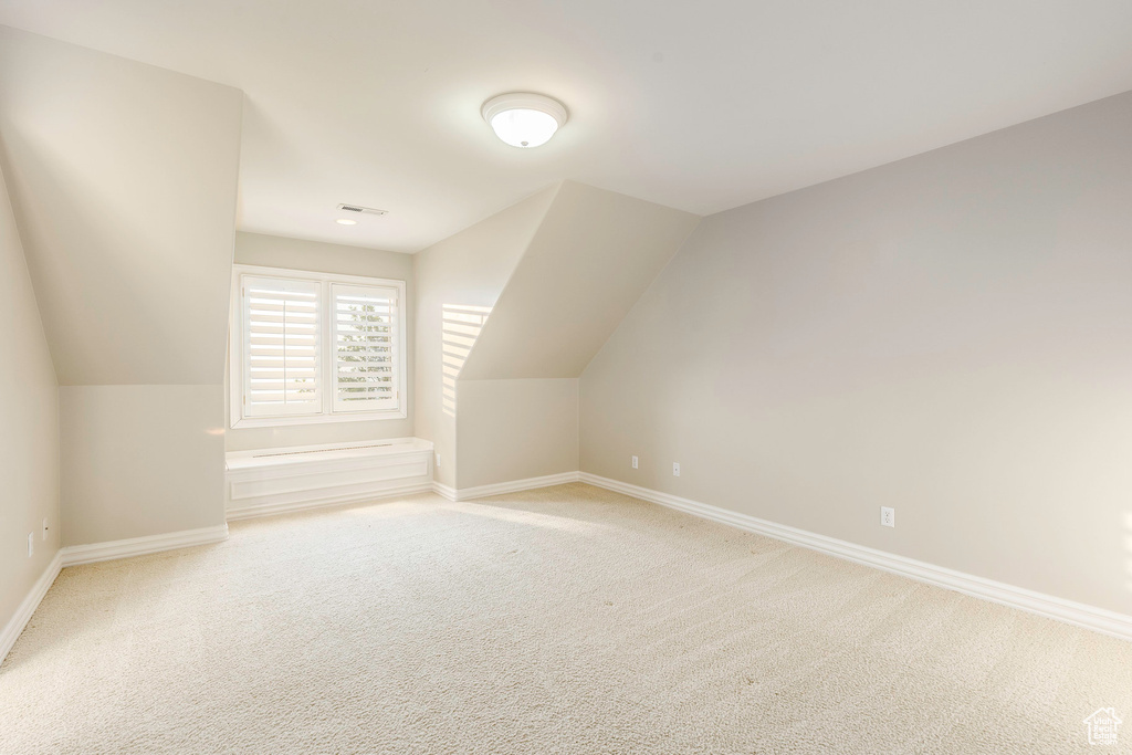 Bonus room featuring lofted ceiling and light carpet