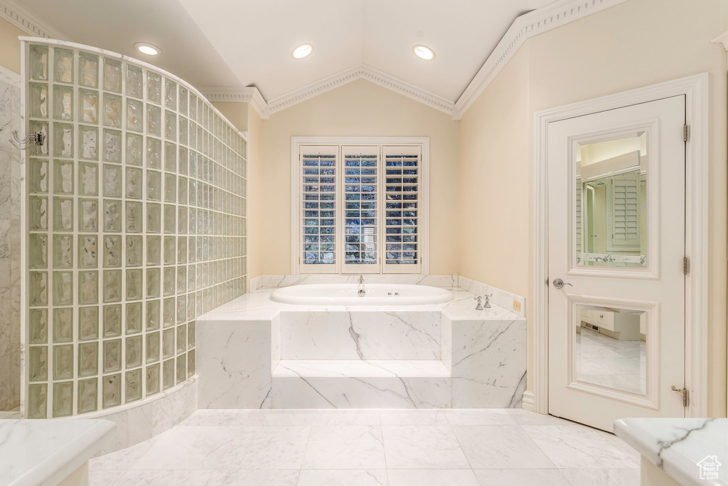 Bathroom with lofted ceiling, separate shower and tub, ornamental molding, and tile patterned floors