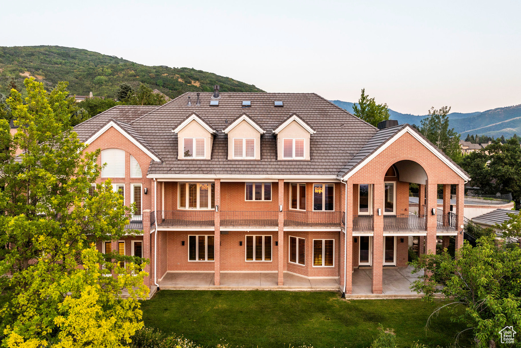 Rear view of property with a mountain view, a yard, a patio, and a balcony