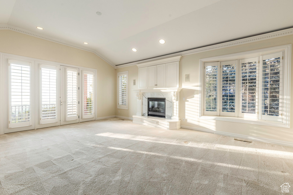 Unfurnished living room with lofted ceiling, crown molding, a high end fireplace, and light carpet