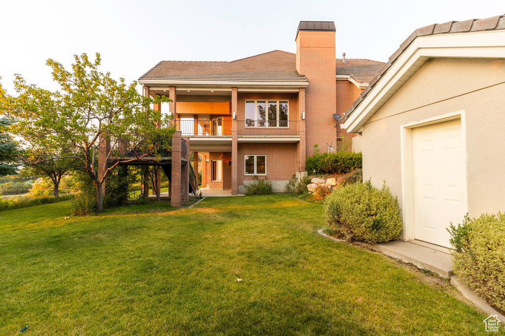 Rear view of property featuring a balcony and a yard