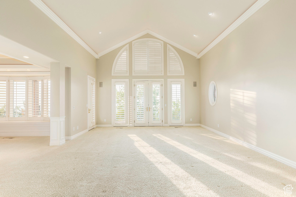 Carpeted spare room featuring crown molding, french doors, and high vaulted ceiling